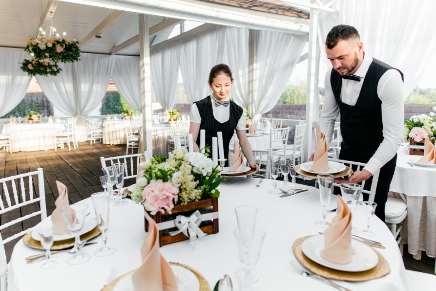 Two male and female waiters serve tableware on the table in the restaurant